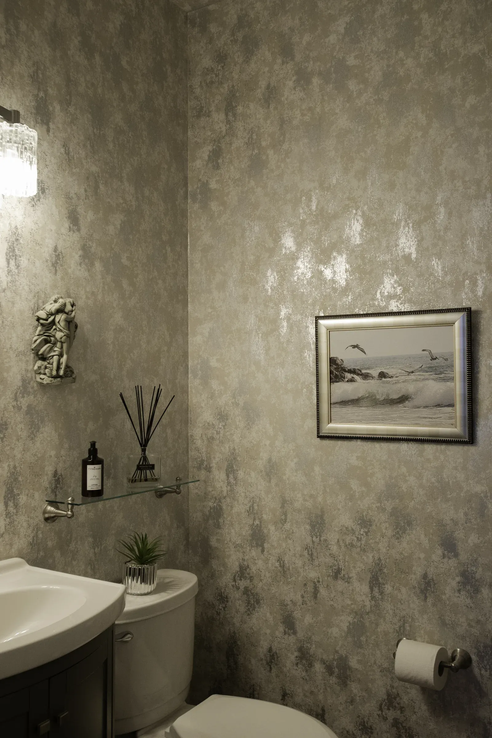 Powder room with softly textured wallcovering and decorative lighting