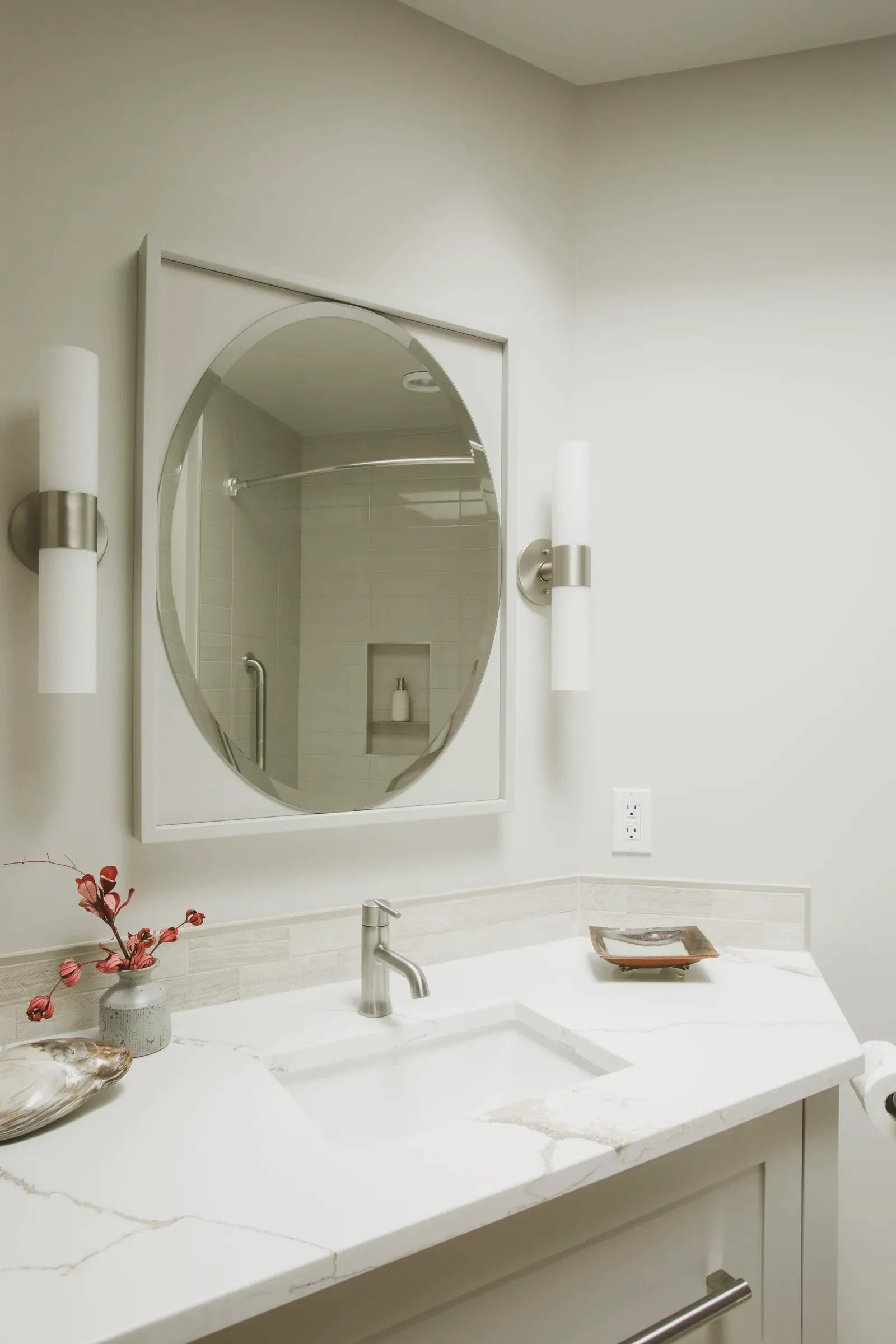 Streamlined vanity with an oval mirror and soft neutral finishes