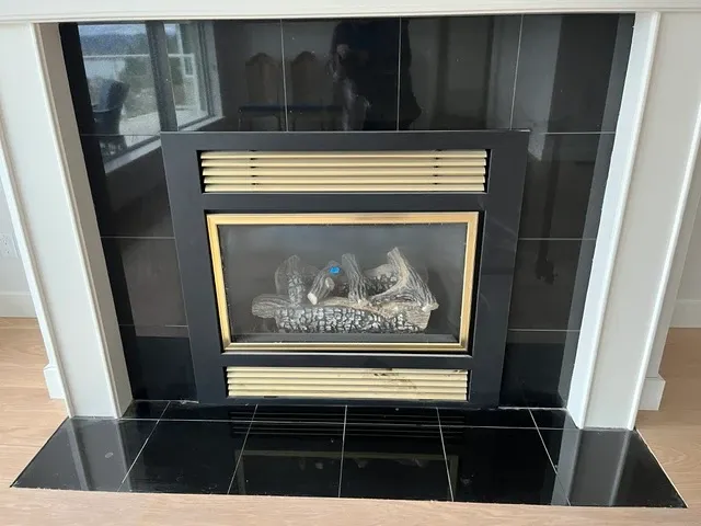 Original fireplace with a black tile surround, brass trim, and a white mantel