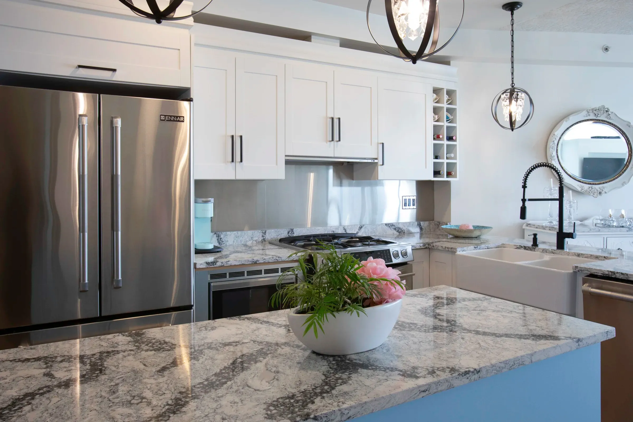 A bright white kitchen with expressive stone counters and black fixtures
